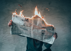 Newspaper on fire while a man reads it