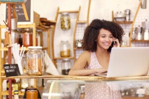 Image of a small business owner making a call on her phone while using her laptop.