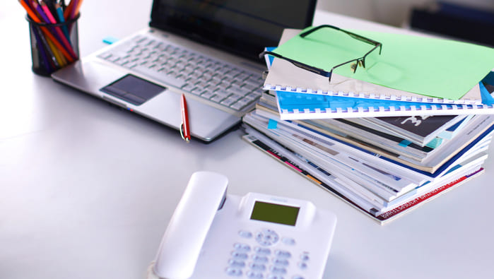 Stock image of telephone on a table with laptop and paper files